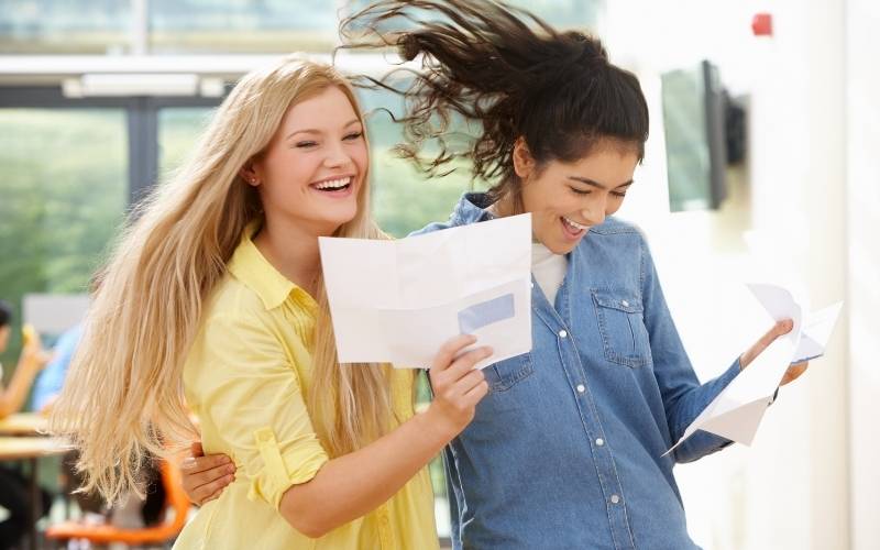 Zwei Schüler im Teenageralter feiern das erfolgreiche Prüfungsergebnis